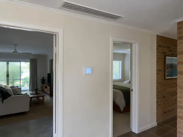 Ceiling ducted grille and wall controller in a cream hallway with brick feature wall in Currumbin Waters